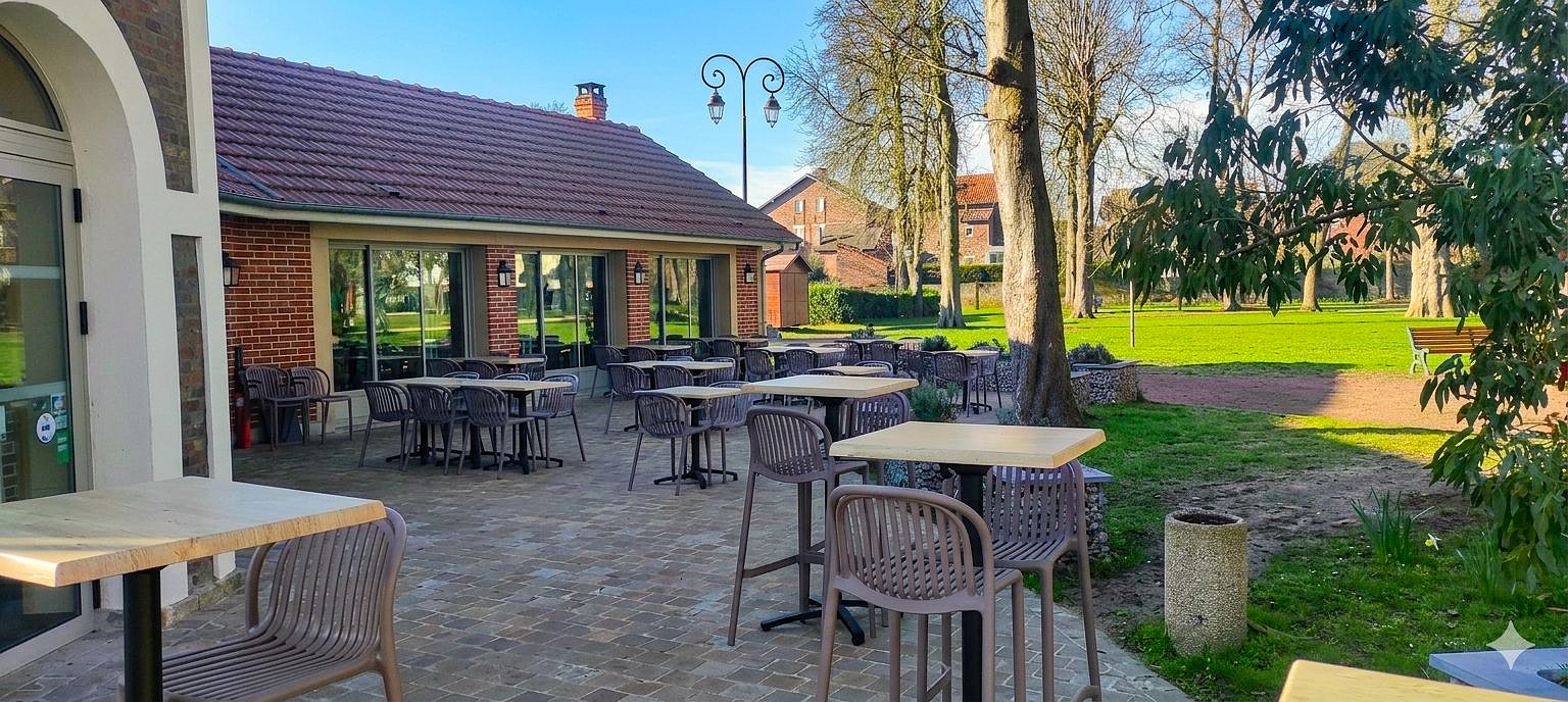 Photo de la terrasse exterieur. On y voit des chaises, des tables et des arbres.